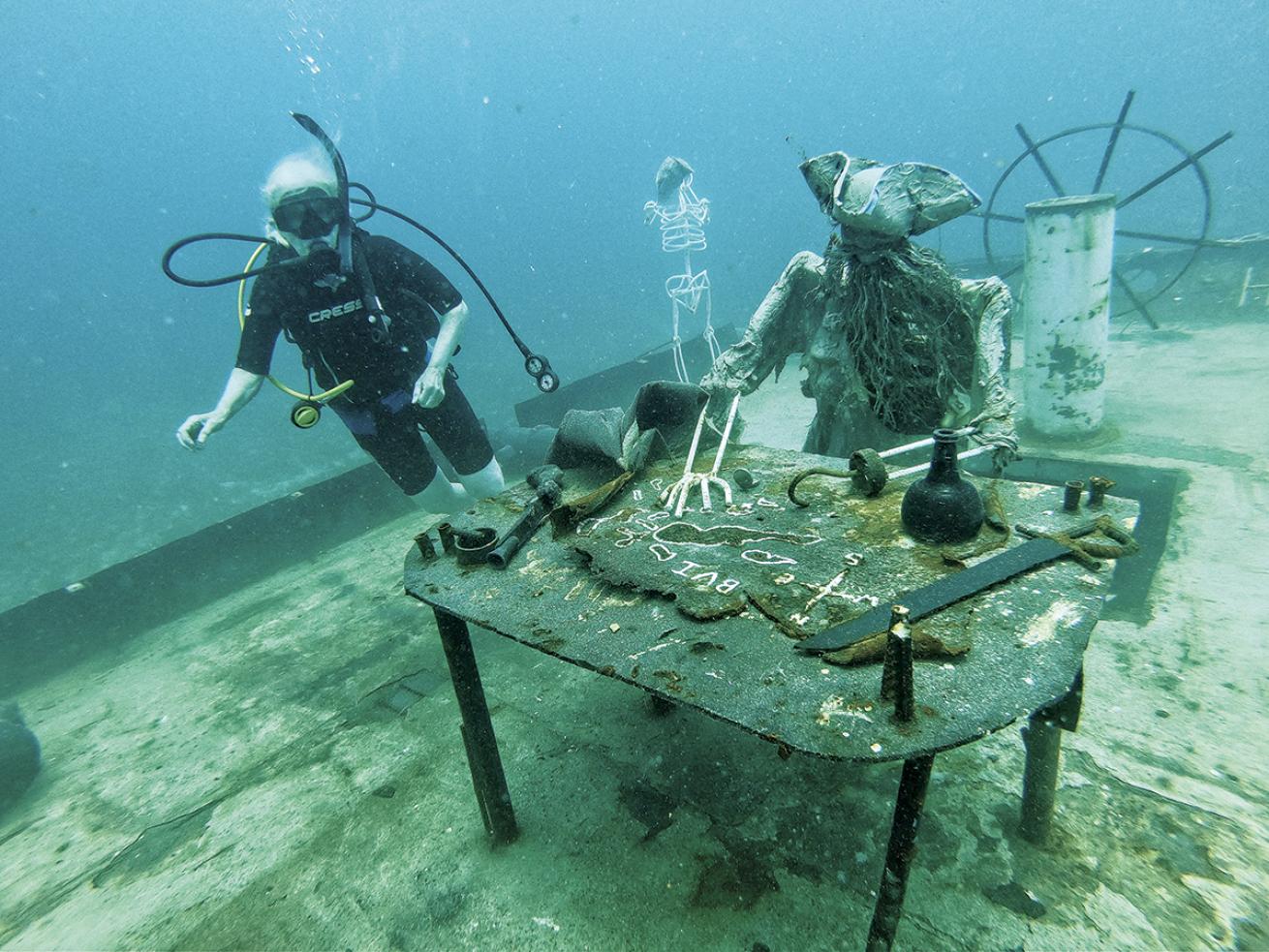 A diver swims past a rebar pirate skeleton sitting on the wreck of the Willy T.