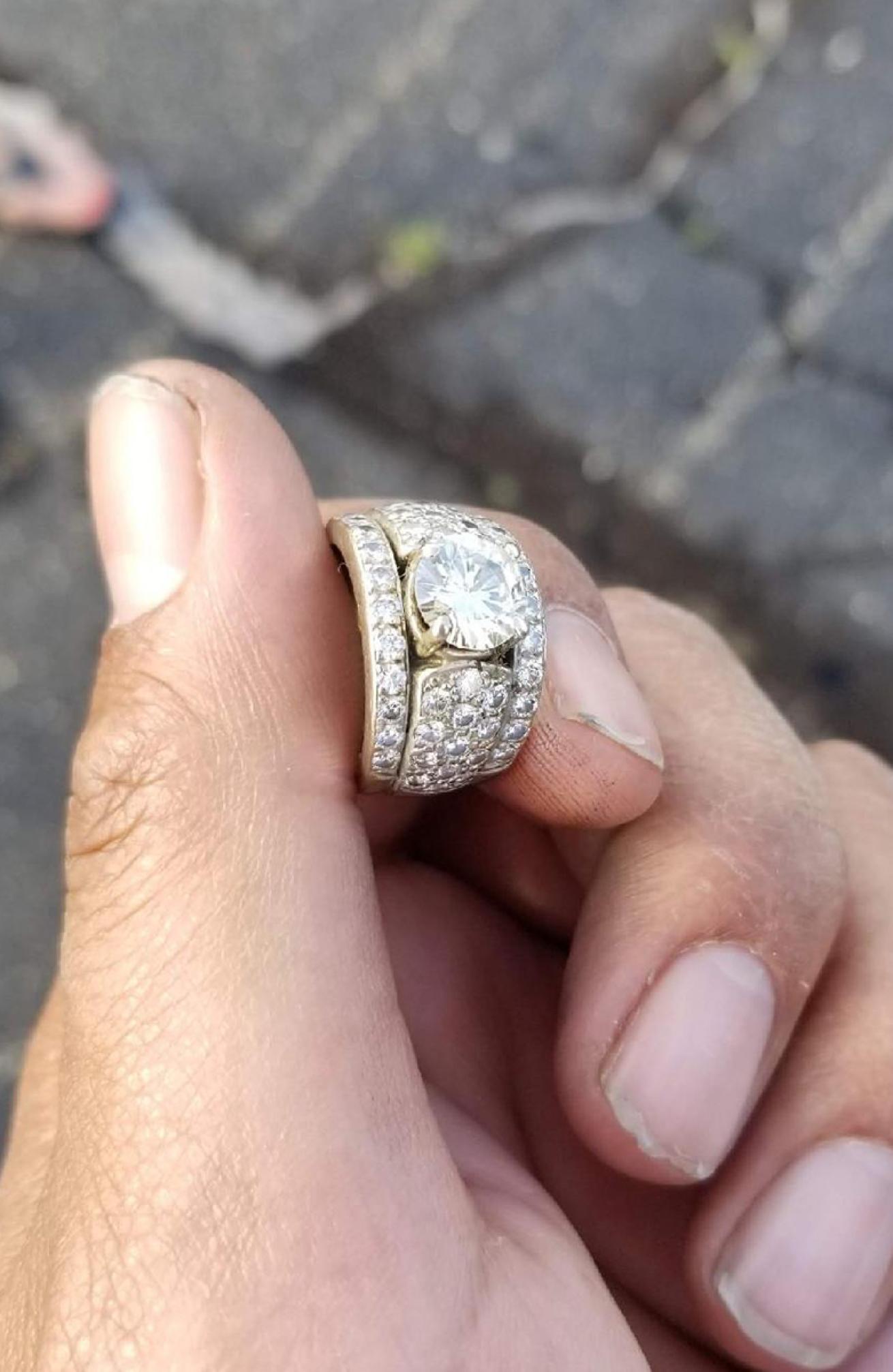 Close up of aarge gold ring encrusted in diamonds held in a hand